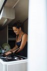 Donna con panino lavare i piatti nel camper durante una vacanza. — Foto stock