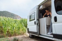 Woman with bun washing dishes in motorhome during a vacation. — Stock Photo
