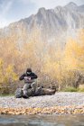 Un pescatore della mosca prepara il suo ingranaggio in una regolazione bella della montagna. — Foto stock