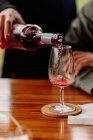 Наливая вино в бокал на деревянный стол — стоковое фото