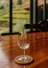Wein in ein Glas auf einen Holztisch gießen — Stockfoto