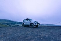 4x4 estacionado en la cima de la colina en las tierras altas Islandia junto al volcán - foto de stock