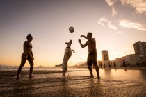 Couple playing soccer with dog on the water front in Copacabana Beach — Stock Photo