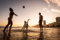 Coppia che gioca a calcio con cane sul lungomare a Copacabana Beach — Foto stock
