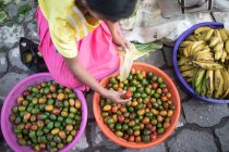 Mujer mayor vendiendo frutas orgánicas (Jocotes) en el mercado local - foto de stock