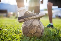 Fußballer legt alten Schuh auf zerrissenen Fußballball — Stockfoto