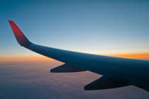 Flügel eines Flugzeugs mitten in der Luft bei Sonnenuntergang fliegt über den Planeten Erde. — Stockfoto