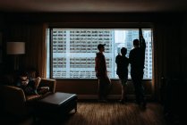 Man and boys looking out window at tall buildings of the city outside. — Stock Photo