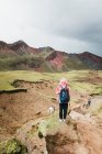 На пагорбі в Перу стоїть молода жінка з рюкзаком. — стокове фото