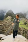 Uma jovem mulher está de pé perto de ruínas de Machu Picchu, Peru — Fotografia de Stock
