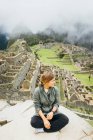 Молодая женщина сидит возле руин Мачу-Пикчу, Перу — стоковое фото