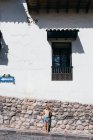Una joven está de pie cerca de una pared blanca en Cusco, Perú - foto de stock