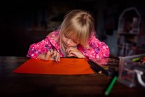 Kleines blondes Mädchen zeichnet an einem sonnigen Tag ein Bild an einem Tisch — Stockfoto