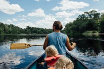 Людина на каное з маленькими дітьми вниз по річці на півночі. — стокове фото
