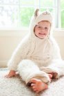 Portrait de jeune garçon heureux en costume de lama assis sur le sol à la maison — Photo de stock