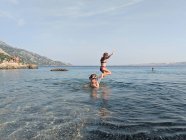 Dos niños jugando y saltando en el mar - foto de stock