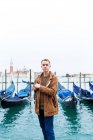 Junger blonder Kerl in brauner Jacke mitten auf den Straßen Venedigs — Stockfoto