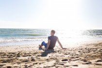 Loira cara turista em jeans aproveitando a praia e o mar — Fotografia de Stock