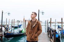 Молодой блондин в коричневой куртке посреди улиц Венеции — стоковое фото