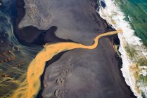 Вид з повітря на плетену оранжеву річку, що тече в океан на півдні — стокове фото
