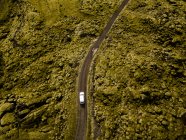 Vue aérienne de la voiture conduisant à travers les roches de lave couvertes de mousse — Photo de stock