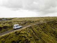 Vista aérea do carro dirigindo através de rochas de lava cobertas de musgo — Fotografia de Stock