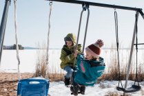 Kinder spielen gemeinsam auf einer Doppelschaukel am See in Schweden — Stockfoto