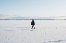 Chico caminando a través de un lago congelado solo en Suecia - foto de stock