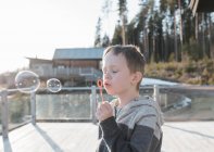 Мальчик раздувает пузыри на балконе дома в Швеции — стоковое фото