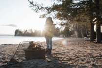 Young boy stood next to a fire on the beach in Sweden — Stock Photo