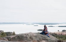 Femme assise sur un rocher regardant une belle vue sur la Suède — Photo de stock