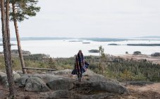 Mujer de pie sobre una roca disfrutando de la hermosa vista en Suecia - foto de stock