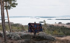 Mulher segurando cobertor de pé em uma rocha com uma bela vista — Fotografia de Stock