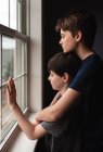 Deux garçons regardant par la fenêtre avec des visages tristes — Photo de stock