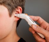 Close up de criança recebendo temperatura tomada com um termômetro de ouvido. — Fotografia de Stock