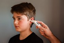 Tween boy getting temperature taken with an ear thermometer. — Stock Photo