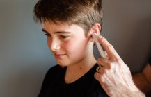 Мальчик-подросток получает температуру с помощью ушного термометра. — стоковое фото