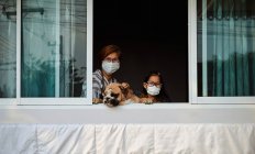 Мати і дочка з собакою залишаються вдома під час епідемії COVID-19. — стокове фото