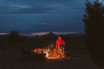 Mujer sentada en una fogata en las montañas. - foto de stock