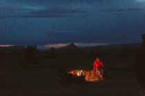 Mulher sentada em uma fogueira nas montanhas. — Fotografia de Stock