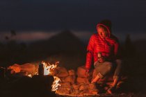 Femme assise sur un feu de camp dans les montagnes. — Photo de stock