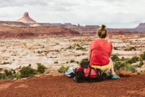 Молода жінка в червоному сидить у пустелі — стокове фото