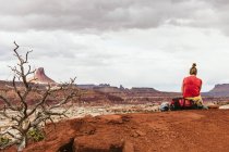 Молодая женщина в красном сидит в пустыне — стоковое фото
