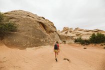 Una giovane donna in rosso che cammina lungo il deserto — Foto stock