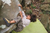 Маленький хлопчик піднімається на скелю на відкритому повітрі — стокове фото
