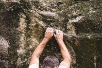 Parte superior de un escalador masculino escalando una roca - foto de stock