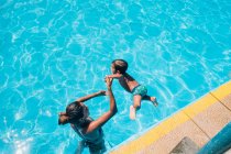 Mujer ayudando a su hijo a saltar a la piscina - foto de stock