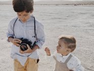 A kid holds a camera and a younger kid stands next to  me — Stock Photo