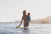 Mère et fils surfant sur une petite vague en mer — Photo de stock