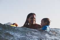 Мать и сын катаются на маленькой волне в море — стоковое фото